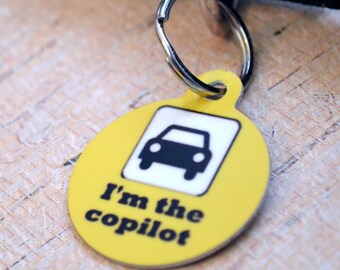 May include: Yellow round dog tag with a black car icon and the text "I'm the copilot".