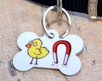 May include: White bone-shaped dog tag with a yellow chick and a red horseshoe magnet. The tag is attached to a black dog collar.