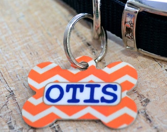 May include: Orange and white chevron dog tag with the name "OTIS" in blue lettering.