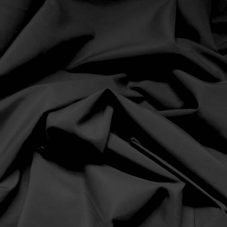 May include: Black fabric with a smooth, silky texture. The fabric is draped and folded, creating soft, flowing lines.