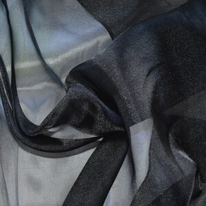 May include: Black sheer fabric with a subtle sparkle. The fabric is draped and folded, showing its texture and transparency.