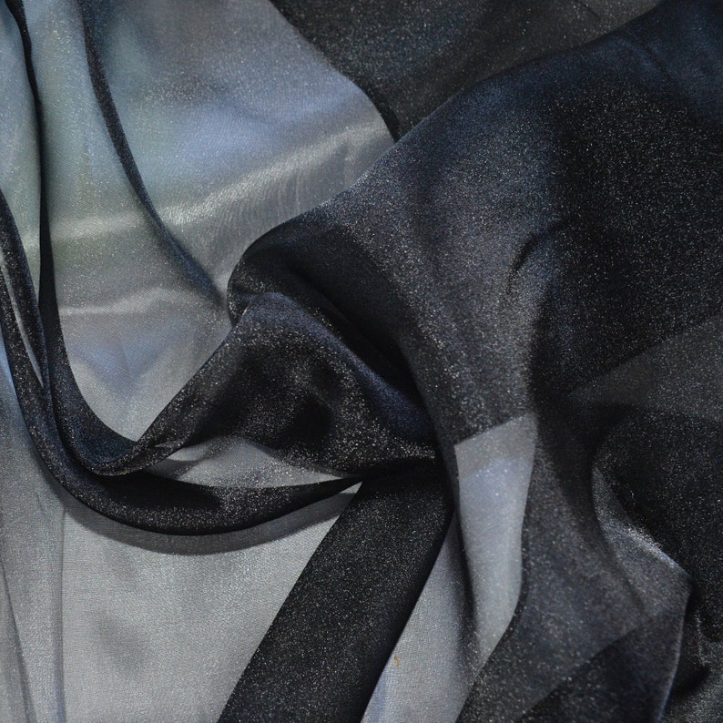 May include: Black sheer fabric with a subtle sparkle. The fabric is draped and folded, showing its texture and transparency.