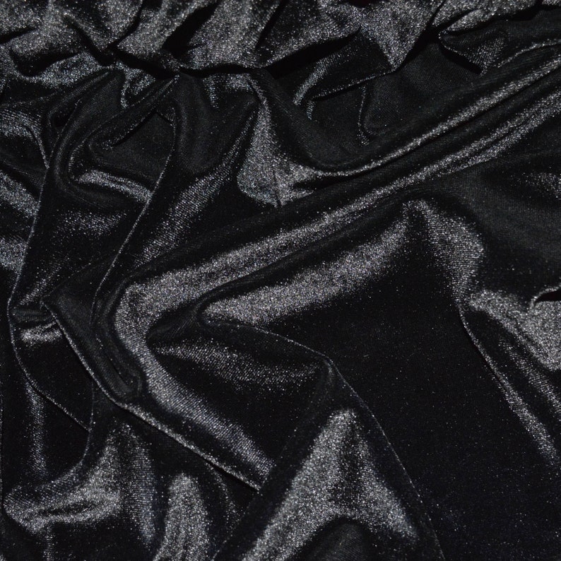 May include: Black velvet fabric with a smooth, shiny texture. The fabric is draped and folded, creating a luxurious and elegant look.