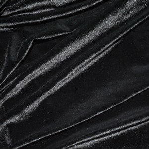 May include: Black velvet fabric with a subtle shimmer. The fabric is draped and folded, showing its texture and sheen.