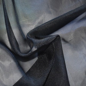 May include: Black sheer fabric with a subtle sparkle. The fabric is draped and folded, showing its texture and sheen.