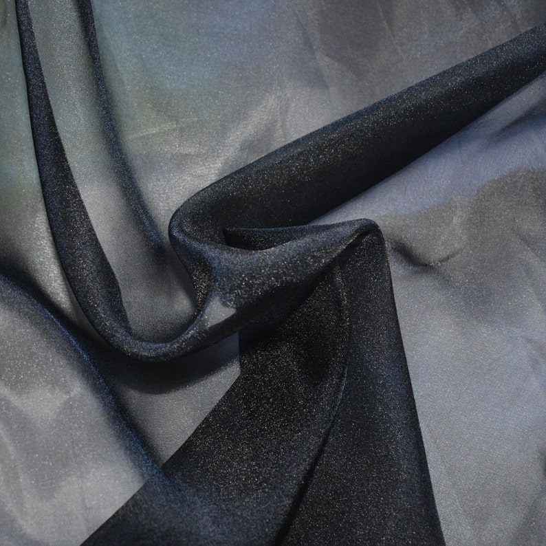 May include: Black sheer fabric with a subtle sparkle. The fabric is draped and folded, showing its texture and sheen.