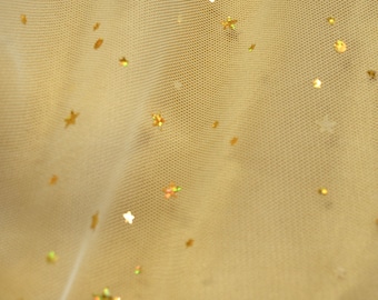 May include: A pale yellow tulle fabric with gold glitter stars scattered throughout.