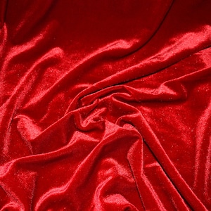 May include: Close-up of a vibrant red velvet fabric with a soft, lustrous sheen. The fabric is draped, creating flowing folds and shadows that highlight its texture. The rich color and tactile appearance suggest luxury and elegance.