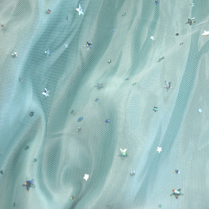 May include: Light blue tulle fabric with silver star-shaped sequins scattered throughout.