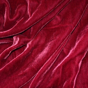 May include: Close-up of a deep red velvet fabric with soft folds and a smooth texture.