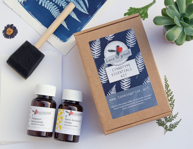 May include: Cyanotype Essentials Kit in a brown box with a blue and white fern pattern. The kit includes two brown glass bottles labeled "A Potassium Ferricyanide" and "B Ferric Ammonium Citrate".