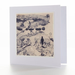 Può includere: Un biglietto bianco con una stampa astratta blu e bianca di una persona in piedi in un paesaggio. La stampa è incorniciata da un bordo bianco.
