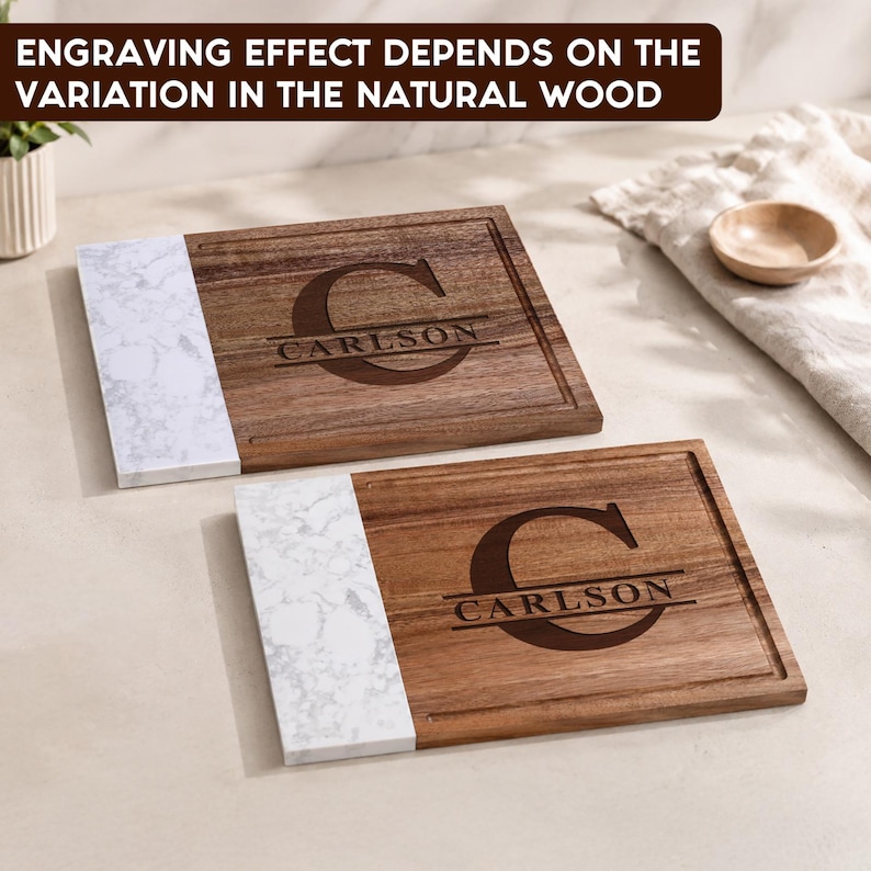 May include: Two rectangular cutting boards featuring a combination of natural brown wood and white marble-patterned sections. Each board is engraved with a large letter C and the name CARLSON. Text reads: ENGRAVING EFFECT DEPENDS ON THE VARIATION IN THE NATURAL WOOD.