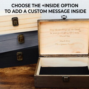 K&ouml;nnte beinhalten: Holz-Andenkenboxen in Natur, Grau und Schwarz. Die offene Box zeigt eine eingravierte Nachricht: "May the teachings of the Torah be your guide along life's way. Mazel Tov. Much love, The Lipman Family." Der Text "CHOOSE THE +INSIDE OPTION TO ADD A CUSTOM MESSAGE INSIDE" steht oben.