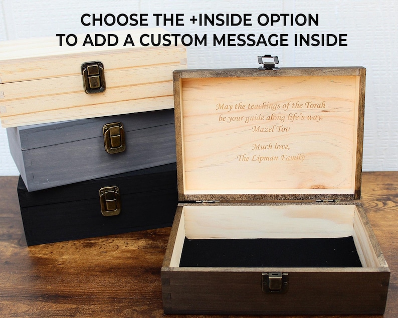 K&ouml;nnte beinhalten: Holz-Andenkenboxen in Natur, Grau und Schwarz. Die offene Box zeigt eine eingravierte Nachricht: "May the teachings of the Torah be your guide along life's way. Mazel Tov. Much love, The Lipman Family." Der Text "CHOOSE THE +INSIDE OPTION TO ADD A CUSTOM MESSAGE INSIDE" steht oben.