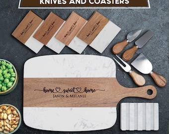 May include: A serving set featuring a wooden and white marble serving board engraved with "home sweet home" and "JASON & MELANIE", four matching coasters, three metal cheese knives with wooden handles, and a white grooved rectangular block.
