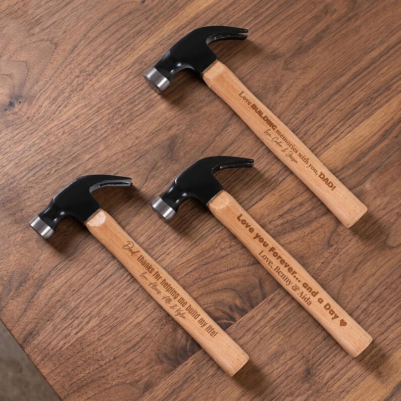 May include: Three claw hammers with black metal heads and light wood handles. Each handle features laser-engraved text: Love BUILDING memories with you, DAD! Love, Caden & Jaxon; Love you Forever... and a Day, Love, Benny & Aida; Dad, thanks for helping me build my life! Love, Alex, Elle & Kyler.
