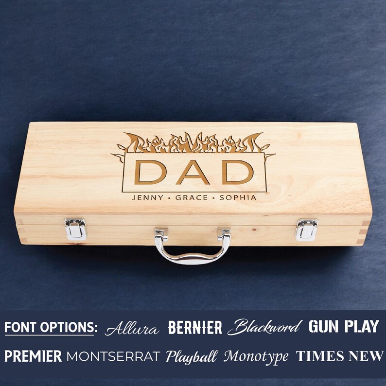 May include: Wooden box with a hinged lid and a metal handle. The box is engraved with the word "DAD" in a flame design. The names "Jenny, Grace, Sophia" are engraved below the word "DAD". The text "FONT OPTIONS: Allura BERNIER Blackword GUN PLAY PREMIER MONTSERRAT Playball Monotype TIMES NEW" is displayed below the box.