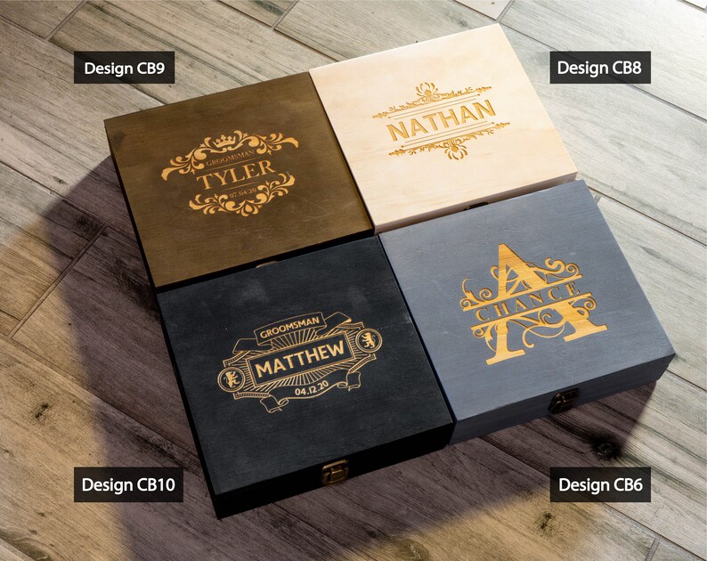 May include: Four wooden boxes with different designs and engravings. The boxes are made of different wood types and have different finishes. The engravings include names, dates, and decorative elements. The boxes are arranged in a grid pattern on a wooden surface. The text on the boxes reads: 'Design CB9', 'Design CB10', 'Design CB8', 'Design CB6', 'GROOMSMAN TYLER', 'GROOMSMAN MATTHEW 04.12.20', 'NATHAN', 'CHANCE'.