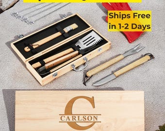 May include: An 11-piece BBQ grill set in a wooden case. The set includes a spatula, tongs, fork, knife, and other grilling tools with wooden handles. The case is engraved with the name "Carlson" and a large letter "C".