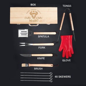 May include: A wooden box with a grill-themed design, featuring the text "Only Fresh Meat Grillin' Chillin' MARC". The box contains a set of grilling tools, including a spatula, fork, knife, brush, tongs, a glove, and four skewers.