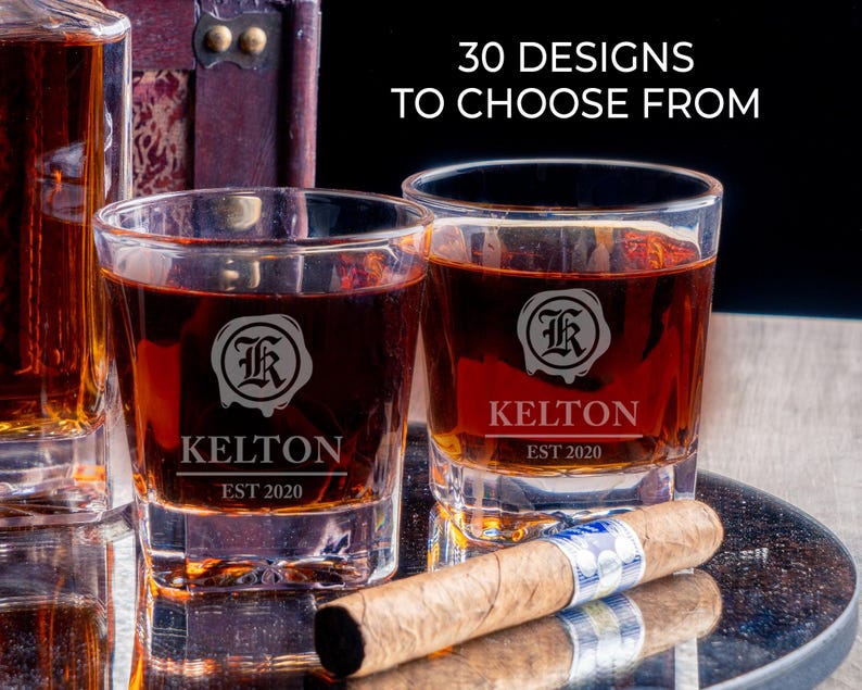 May include: Two clear glass whisky tumblers with etched designs. The tumblers are filled with a dark amber liquid. The text on the tumblers reads "Kelton Est 2020".  30 Designs to Choose From.