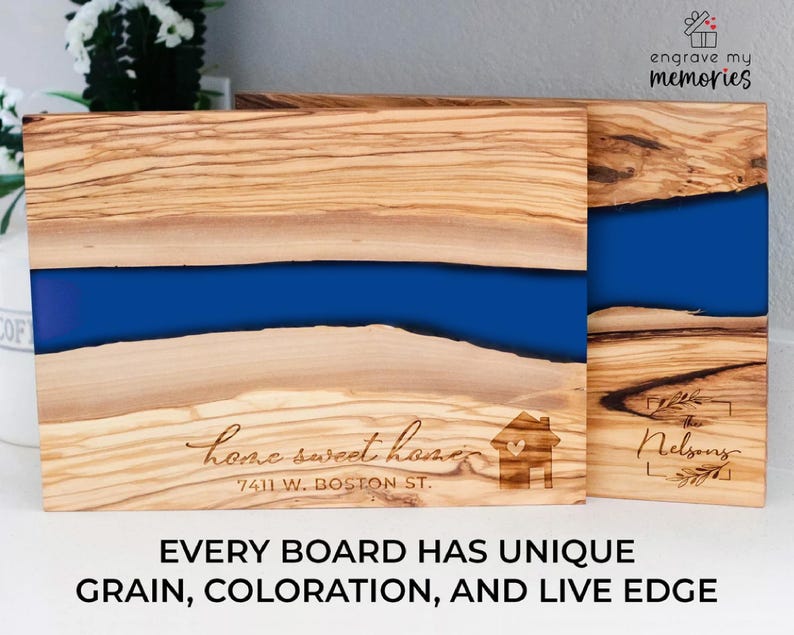 K&ouml;nnte beinhalten: Zwei Holzschneidebretter mit einem blauen Harzfluss-Design. Ein Brett ist mit "home sweet home" und einer Adresse graviert. Das andere Brett ist mit "The Nelsons" graviert. Der Text "EVERY BOARD HAS UNIQUE GRAIN, COLORATION, AND LIVE EDGE" steht unten.
