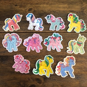 Puede incluir: Diez pegatinas de pony de dibujos animados de colores con diferentes poses y expresiones. Las pegatinas están impresas en papel blanco y tienen un acabado brillante.