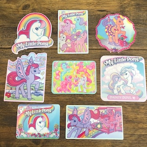 Op de afbeelding: Zeven kleurrijke stickers met My Little Pony-personages. De stickers hebben allemaal verschillende ontwerpen en tonen verschillende pony's. De stickers zijn allemaal in cartoon-stijl en perfect om elke project een vleugje whimsy te geven.
