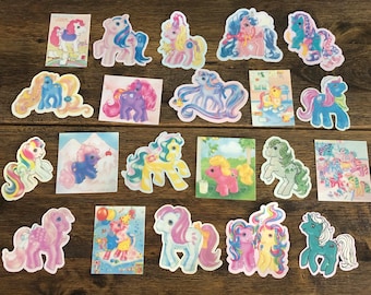 May include: A collection of 20 colorful pony stickers featuring various poses and designs. The stickers are on a wooden surface.