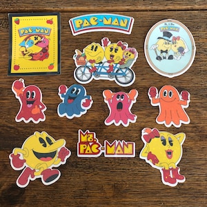 Könnte beinhalten: Ein Set mit neun Pac-Man-Stickern mit verschiedenen Charakteren aus dem klassischen Videospiel. Die Sticker zeigen Pac-Man, Ms. Pac-Man, Blinky, Pinky, Inky, Clyde und einen Hochzeitssticker mit Mr. und Ms. Pac-Man.