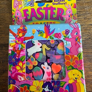 May include: A Lisa Frank Easter eraser set. The box features a yellow top with the words "Lisa Frank" and "Easter" in bright colors. The lower box has a variety of colorful erasers in the shape of Easter eggs, bunnies, and other spring-themed images.