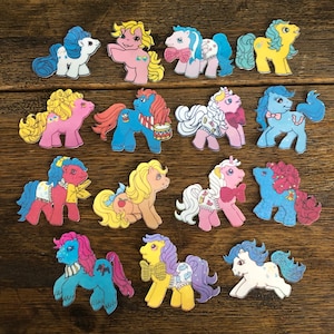 May include: A collection of 15 colorful My Little Pony figurines. The ponies are all different colors and have different hairstyles. Some of the ponies are wearing accessories, such as hats, scarves, and jewelry.