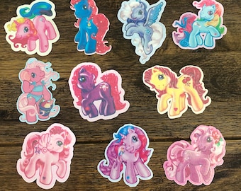 May include: Ten colorful My Little Pony stickers featuring different pony characters with various hairstyles and accessories. The stickers are on a wooden background.