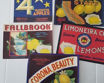 May include: A collection of vintage fruit crate labels. The labels feature text and illustrations of apples and lemons. The labels include the text "Four Star Brand Washington Apples", "Golden State", "Fallbrook", "Limoneira Co. Lemons", and "Corona Beauty".