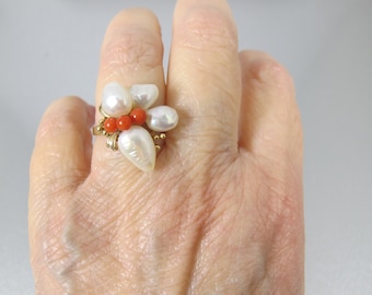 Può includere: Un anello d'oro con un gruppo di perle bianche e perle di corallo rosso a forma di fiore.