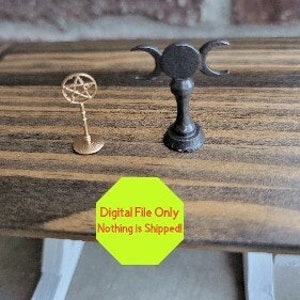 May include: Two small decorative items: a gold-colored pentacle on a stand and a black triple moon goddess symbol. The items are displayed on a wooden surface. A yellow octagon with the text "Digital File Only Nothing is Shipped!" is in the foreground.