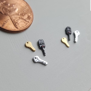 May include: Four miniature keys, two gold, one silver, and one black. The keys are on a white surface.