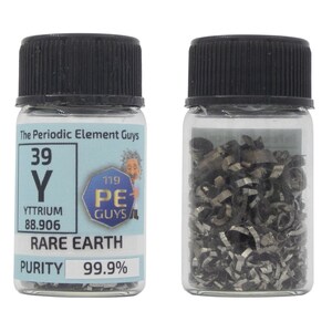 May include: A small glass jar with a black lid containing a sample of yttrium metal. The jar has a label that reads "The Periodic Element Guys" and includes the element's symbol, atomic number, and atomic weight. The label also states "Rare Earth" and "Purity 99.9%".