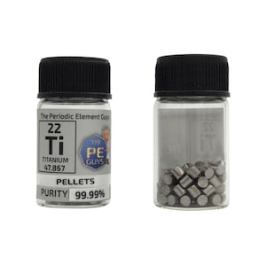 Puede incluir: Un pequeño frasco de vidrio con tapa negra contiene pellets de titanio. El frasco tiene una etiqueta que dice "The Periodic Element Guys" e incluye el símbolo del elemento, el número atómico, el nombre, el peso atómico y la pureza. La etiqueta también incluye un personaje de dibujos animados con el texto "PE Guys".