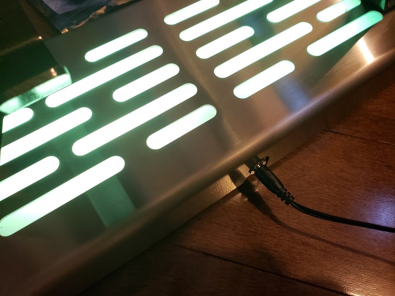 May include: A stainless steel floor mat with a green light pattern, similar to the Star Wars Millennium Falcon, and a black power cord.