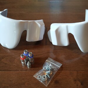 May include: Two white plastic motorcycle fairings with mounting hardware, including screws, nuts, and metal pins.