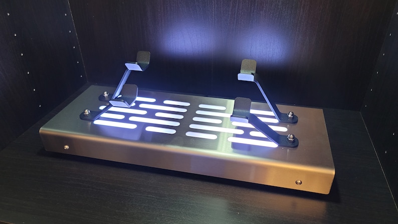 May include: A silver metal platform with a grid pattern and two black metal brackets. The platform is illuminated with white LED lights.