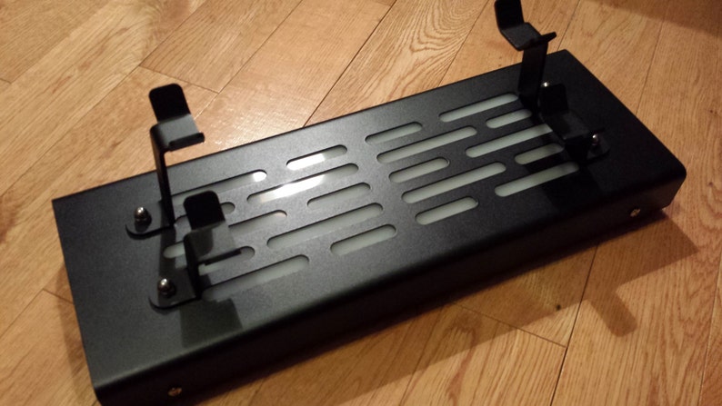 May include: Black metal stand with a grid pattern and two adjustable arms. The stand is designed to hold items upright.