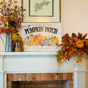 May include: A white fireplace mantel decorated with fall foliage and pumpkins. A sign reads "Meet me at the Pumpkin Patch Hayrides, Caramel, Apples, Cider".