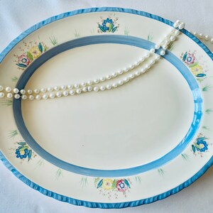 An Art Deco medium oval platter in cream china hand decorated with pastel flowers and blue detail. Made c1930 at the Newhall Pottery.