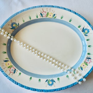An Art Deco small oval platter in cream china hand decorated with pastel flowers and blue detail. Made c1930 at the Newhall Pottery.