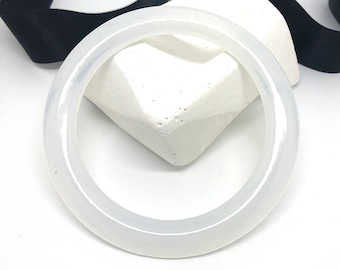 May include: A white jade bangle bracelet. The bangle is smooth and polished, with a slightly translucent appearance.