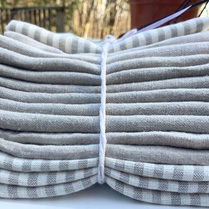 May include: A stack of gray linen kitchen towels with white stripes. The towels are tied together with a white string.