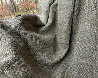 May include: A close-up of a gray woven throw blanket with a textured surface. The blanket is folded and draped over a surface.